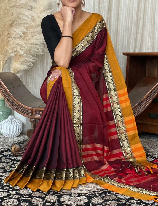 A woman modeling a Magenta Pure Narayanpeth Mercerised Cotton Saree, featuring traditional borders and a blend of cotton and silk fabric.