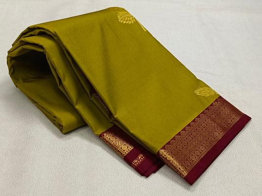 Green saree with maroon border and gold patterns on a light gray background