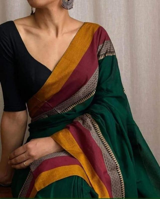 A close-up image of a woman wearing a dark green handloom narayanpeth mercerised cotton saree with a golden yellow, maroon, and gray tribal border.