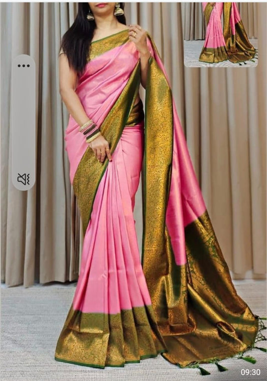 A woman wearing a pink and green banarasi silk saree with a bold pallu, featuring floral patterns and green embellishments.