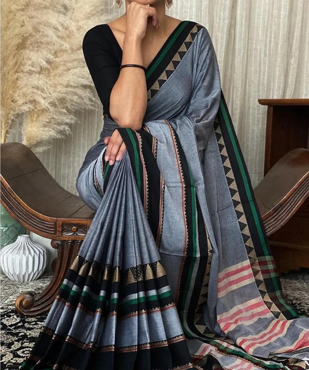 A person showcasing a metallic gray Pure Narayanpeth Mercerised Cotton Saree with a traditional design, featuring geometric patterns and a multicolored border.