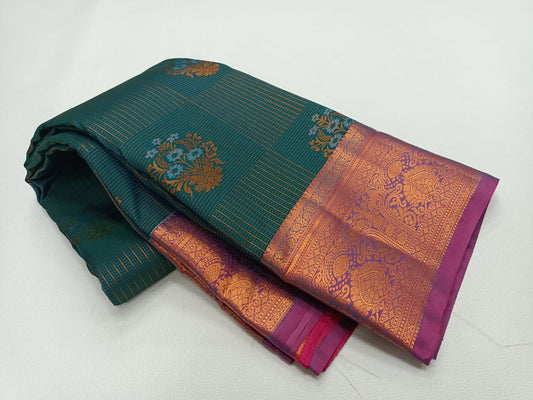 A forest green and magenta silk saree with floral butta designs and a zari border.
