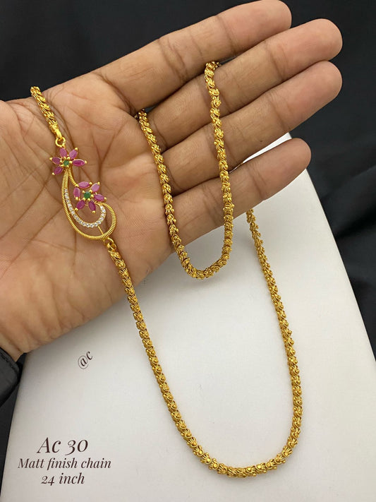 Gold chain with floral pendant held in a hand on a white background