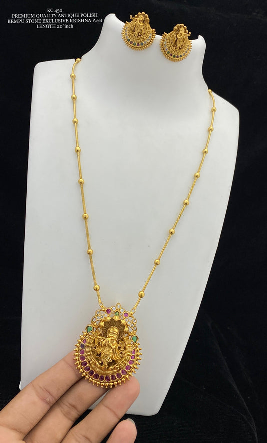 Gold necklace with pendant and matching earrings on a white stand.