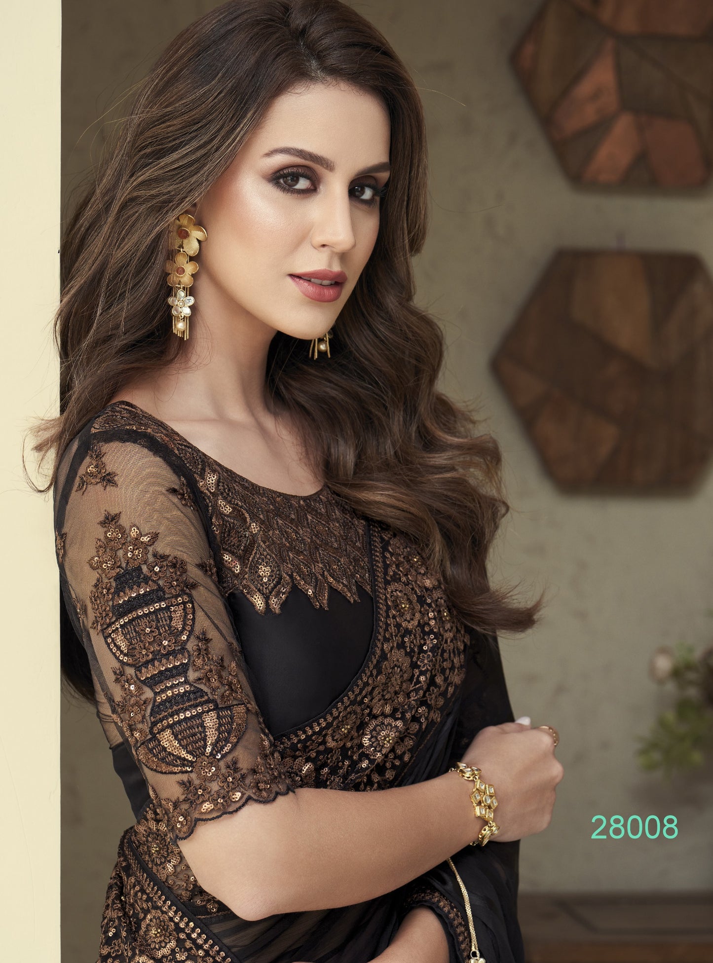 Woman wearing a black and gold embroidered outfit with jewelry indoors.