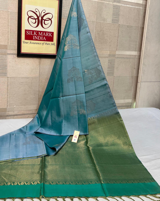 Teal and green saree with a visible brand logo in the background