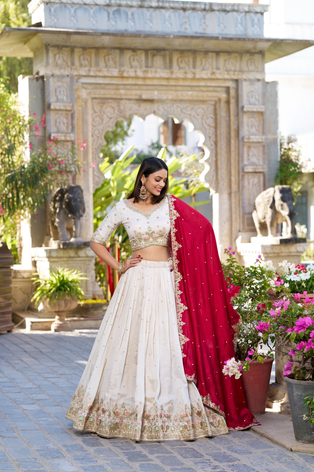 Woman in a traditional outfit standing in front of an architectural structure with floral decorations.