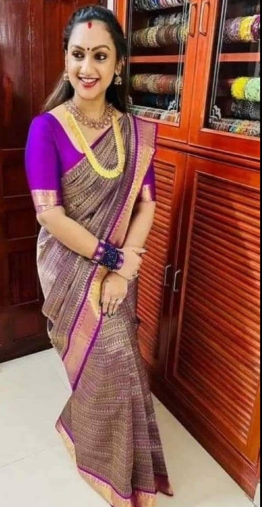 A woman posing in a purple pure Kanchipuram silk saree with gold pure antique zari handloom details and a smile on her face.