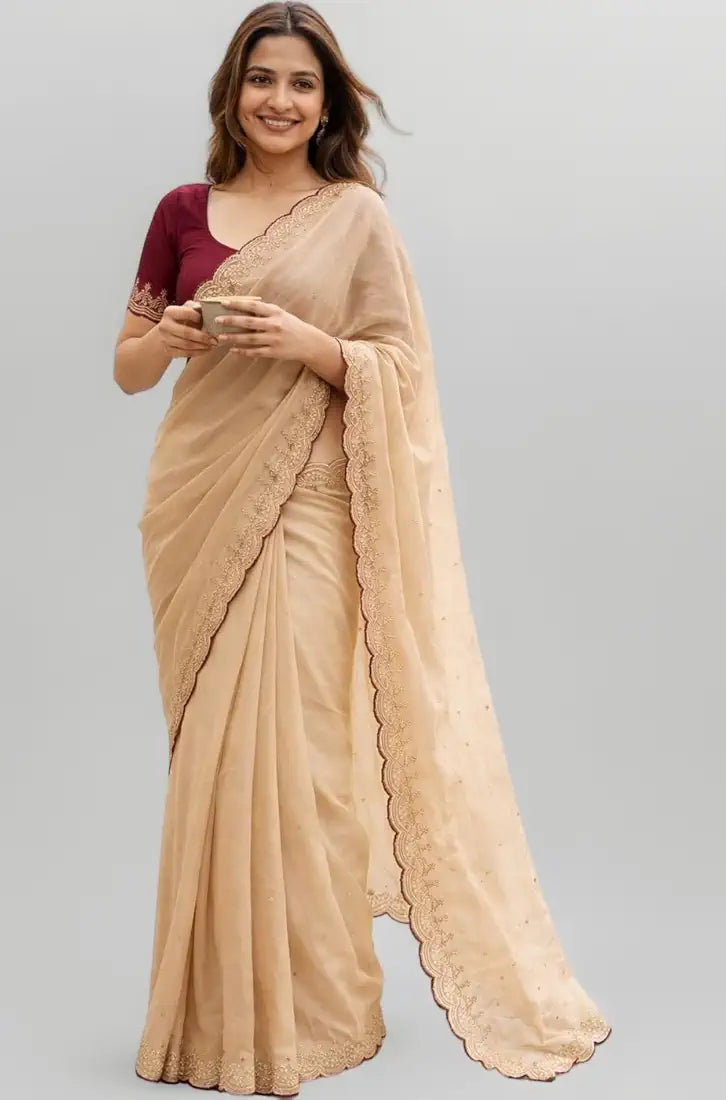 Woman wearing a beige saree with a maroon blouse on a gray background