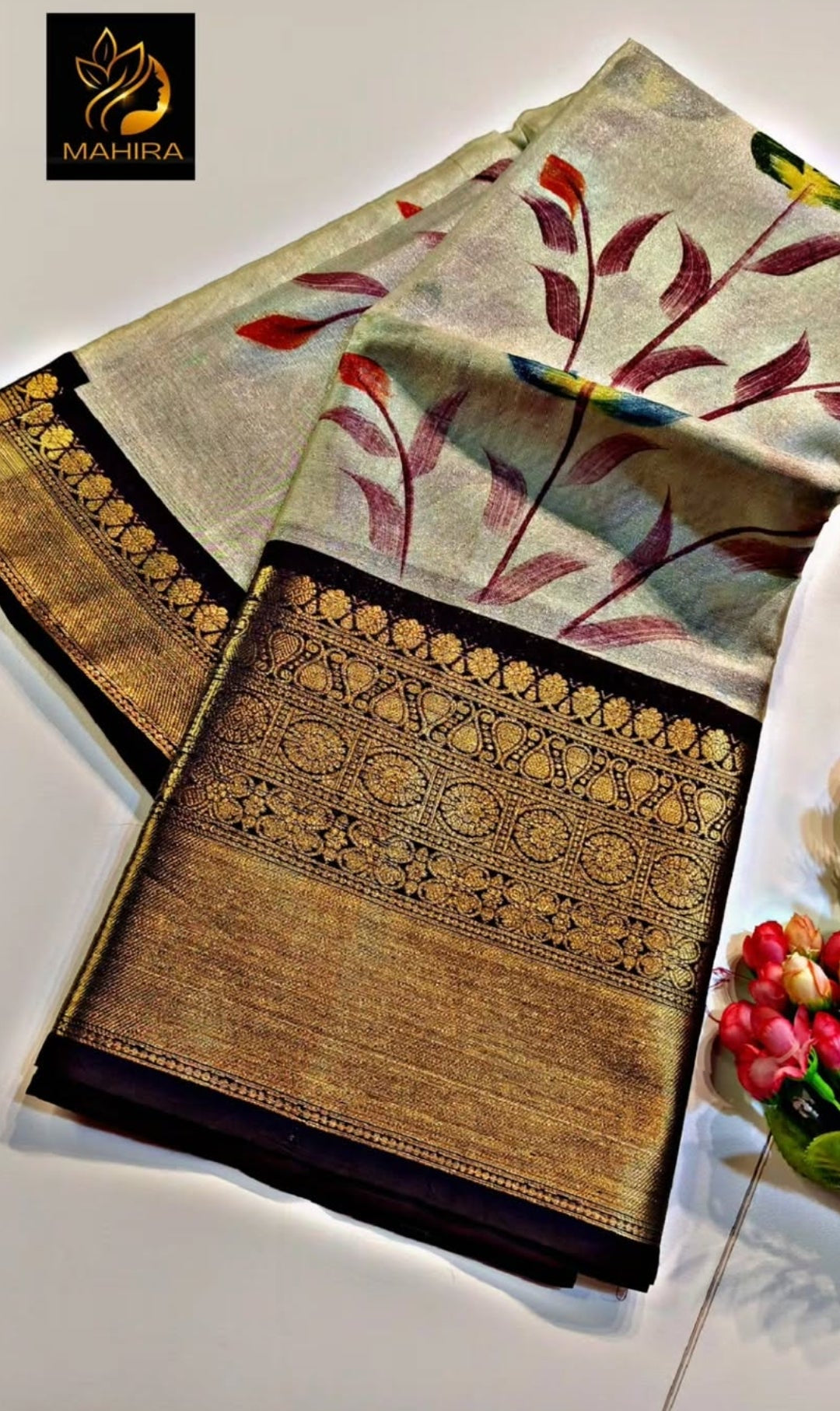 Decorative saree with floral patterns on a white surface, featuring the brand 'Mahira'.