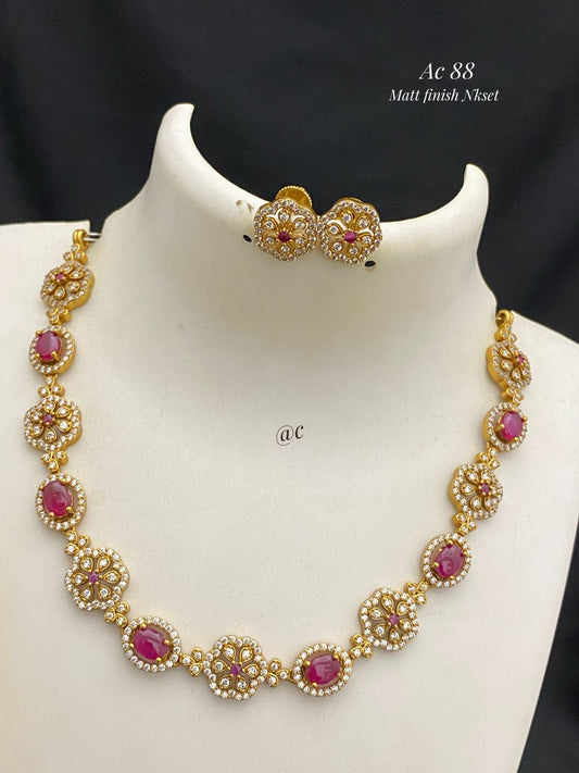 Gold necklace with red gemstones on a mannequin bust against a black background