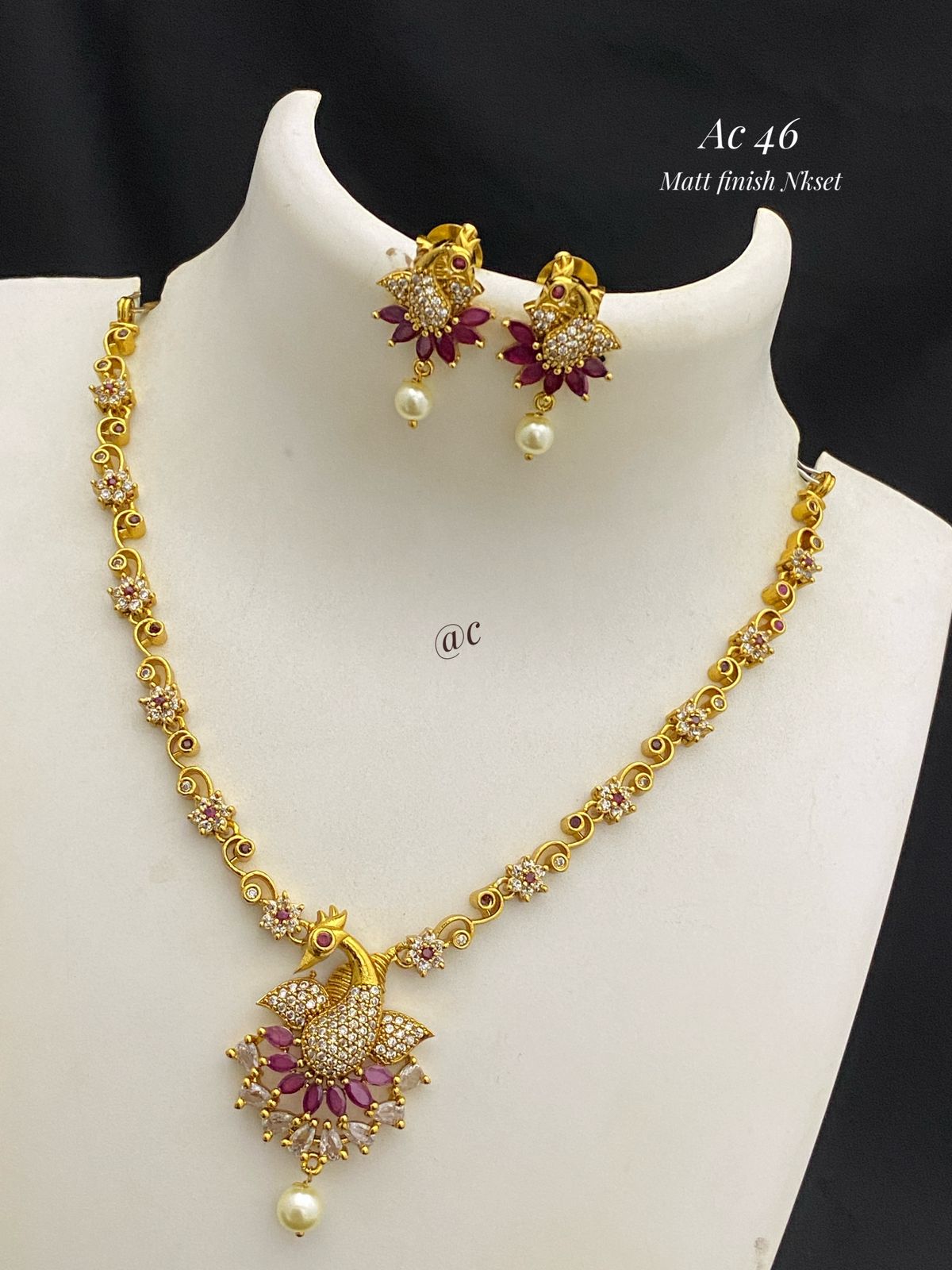 Gold necklace and earrings set on a mannequin with a black background