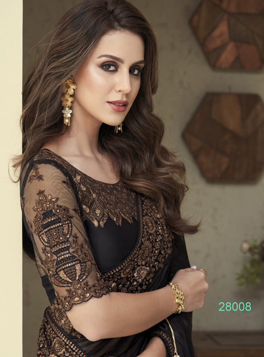 Woman wearing a black and gold embroidered outfit with jewelry indoors.