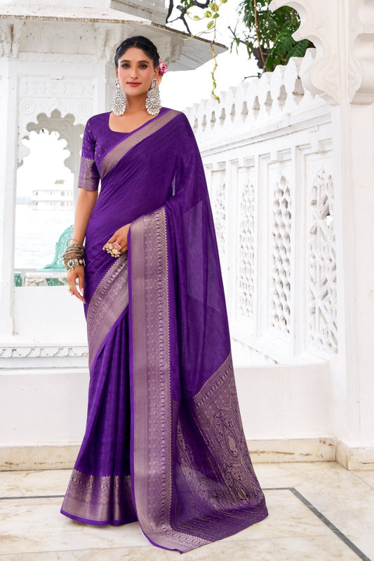 Woman wearing a purple saree with a white architectural background