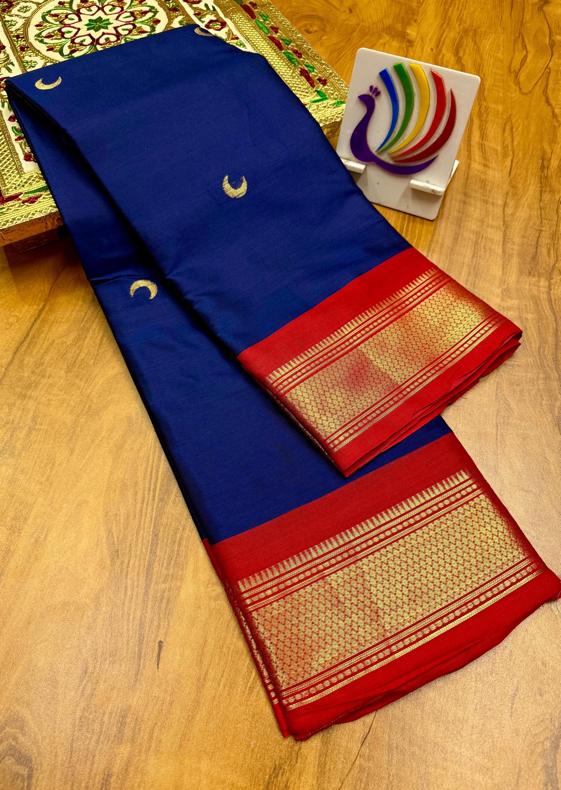 Blue and red saree with gold patterns on a wooden surface