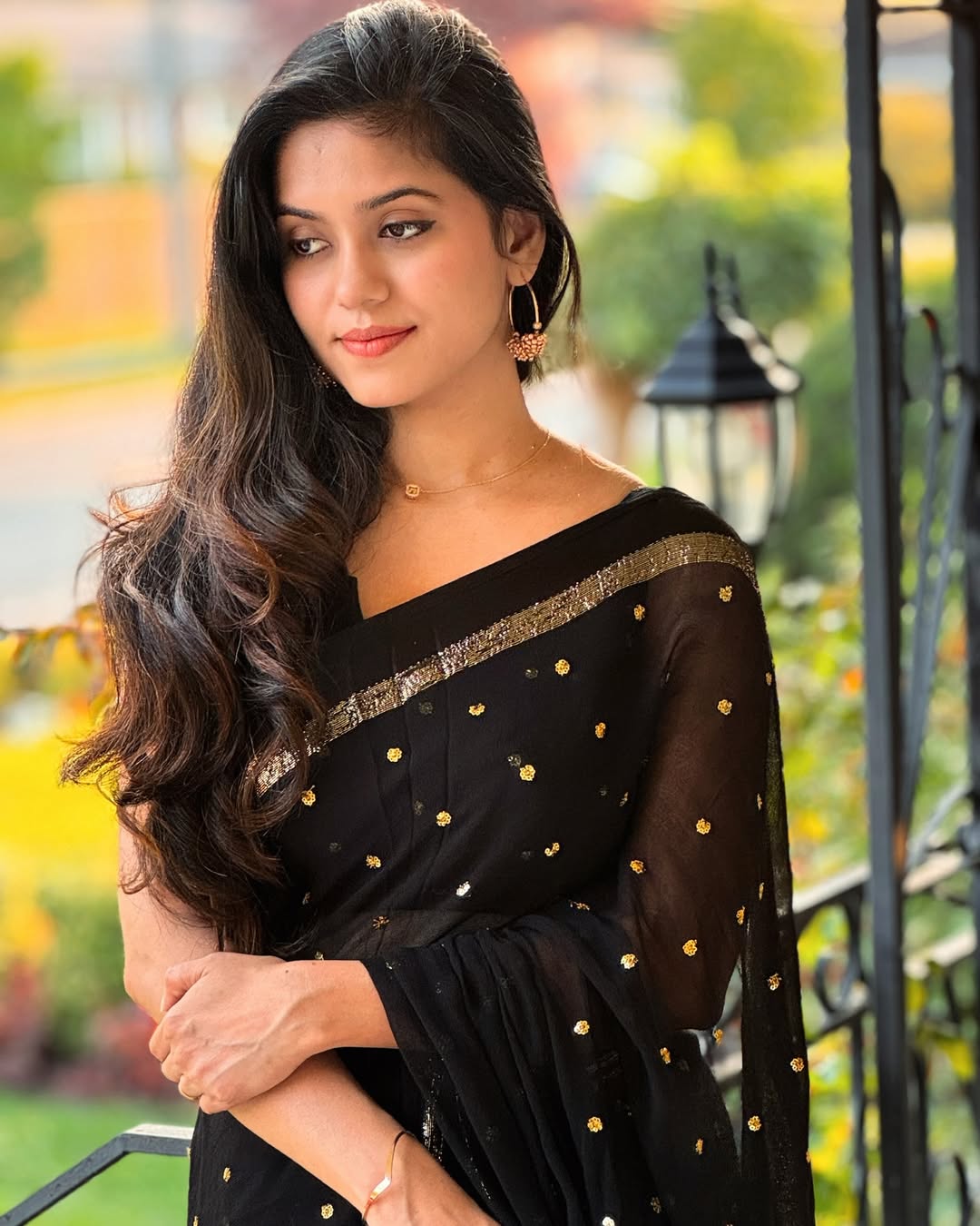 Woman wearing a black saree with gold patterns in an outdoor setting