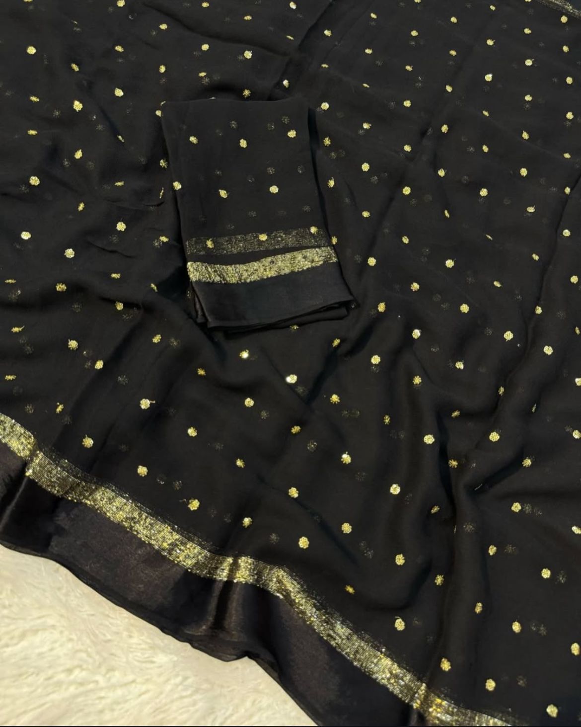 Black fabric with gold polka dots and border on a textured surface