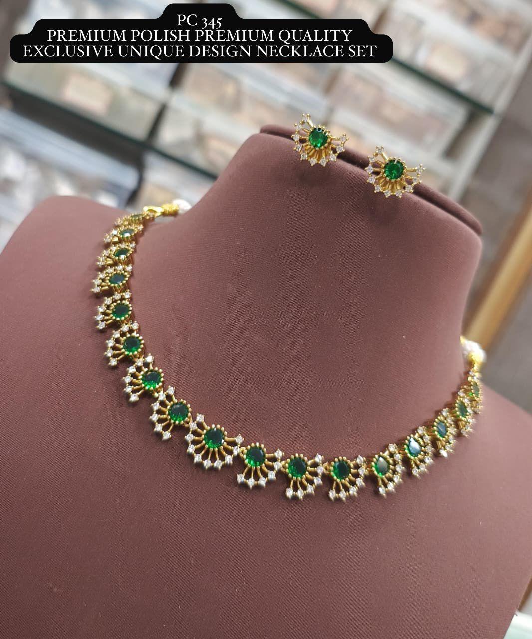 Gold necklace with green gemstones on a mannequin bust.