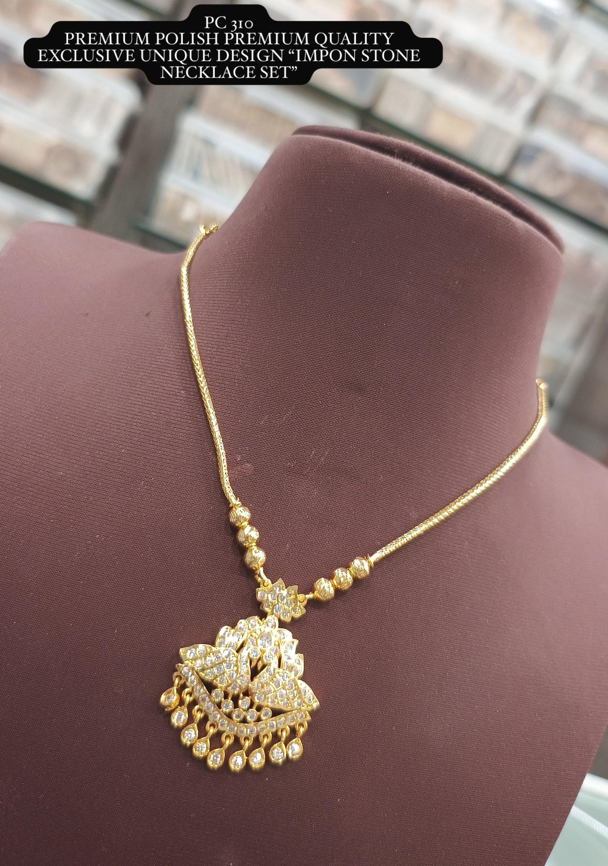 Gold necklace with a decorative pendant on a mannequin bust.