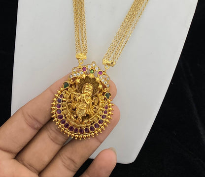 Gold necklace with pendant and matching earrings on a white stand.