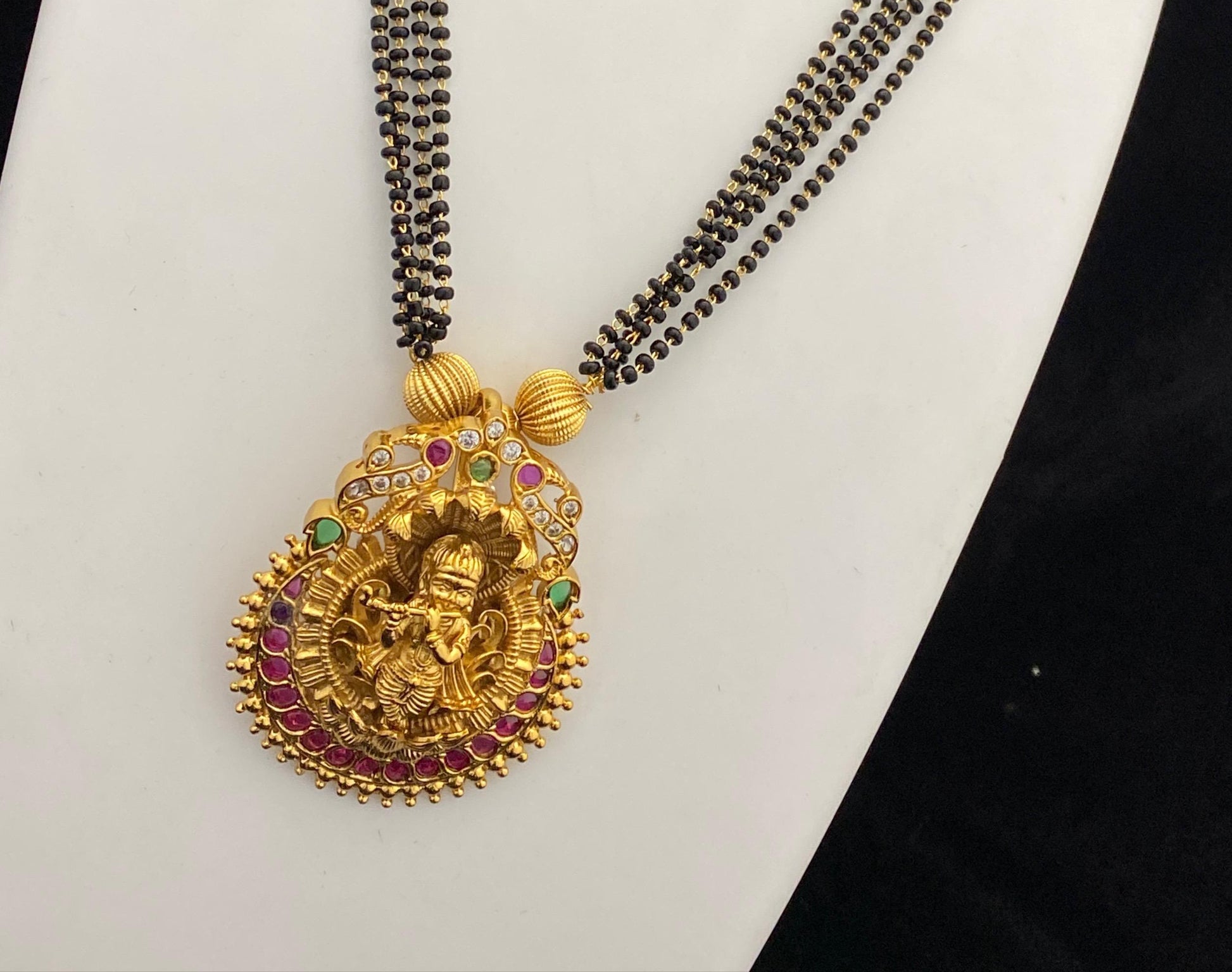 Gold necklace with pendant and matching earrings on a mannequin bust.