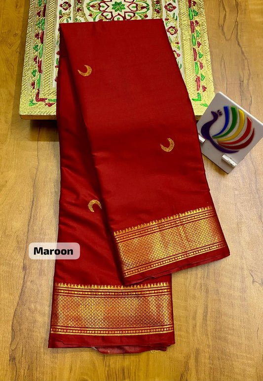 Maroon saree with gold border on a wooden surface