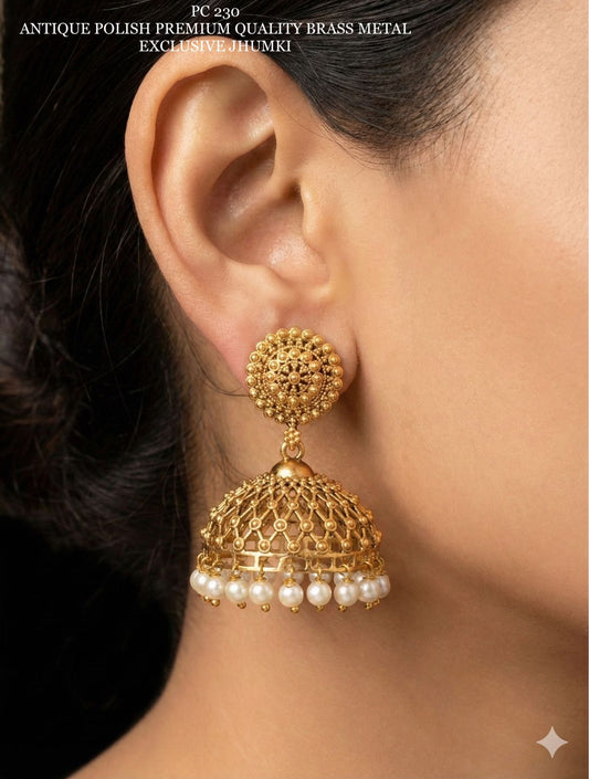 Gold jhumka earring with pearls worn by a person