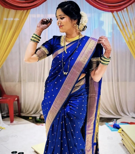 Woman in a blue saree with gold details against a decorated indoor background